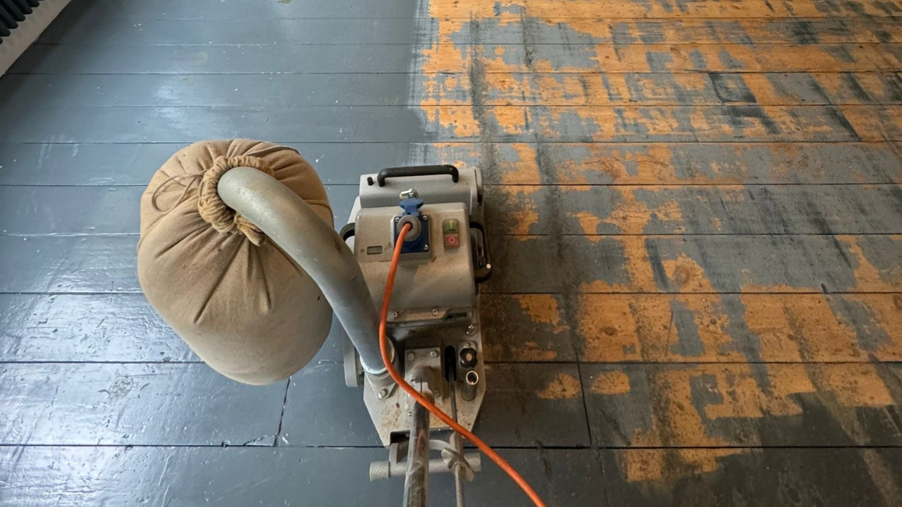Wood Floor Sanding machine stripping grey paint from painted pine floorboards in a Stamford Hill home.