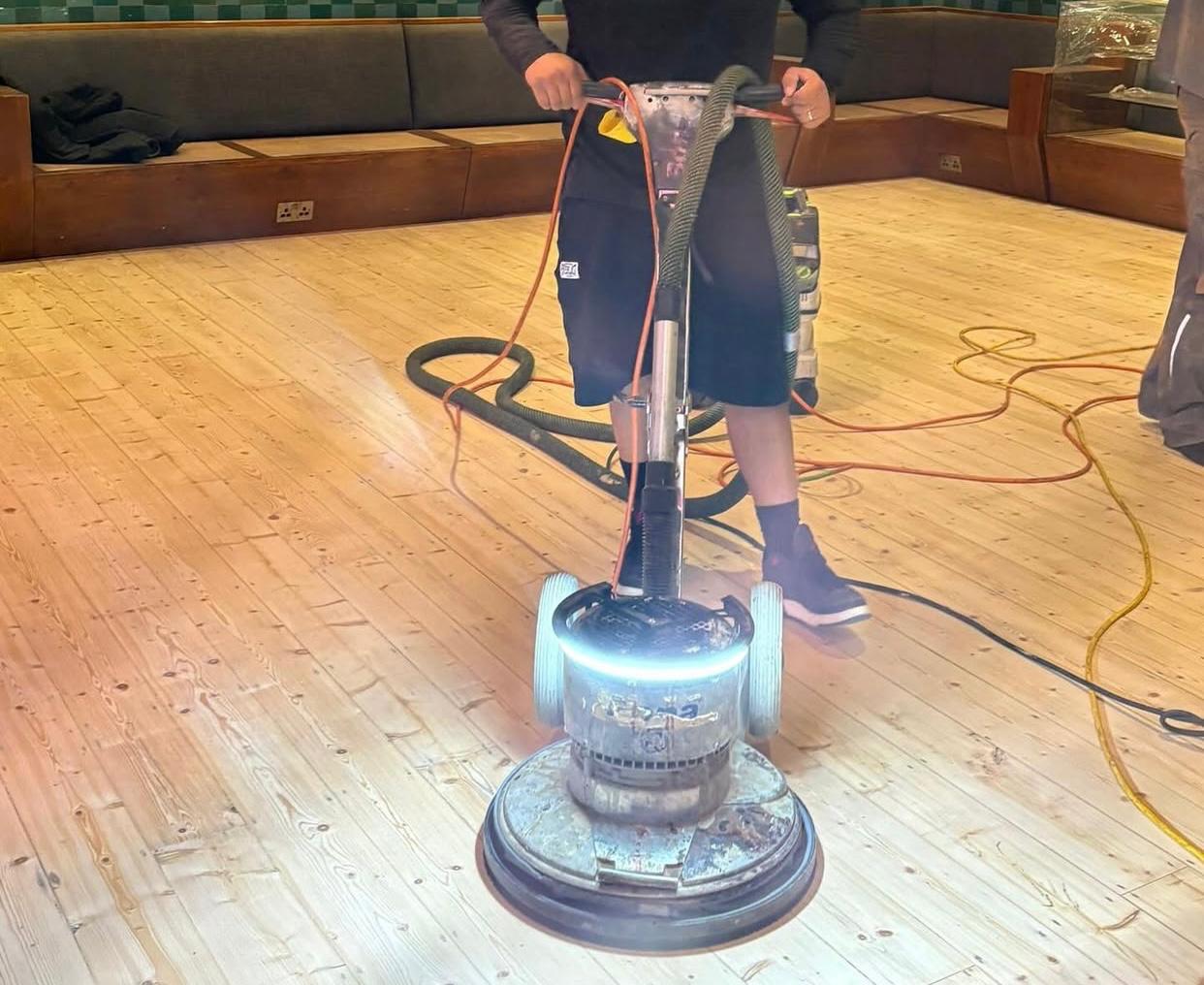 Technician buffing solid pine floorboards during Wood Floor Sanding in a Stamford Hill interior.