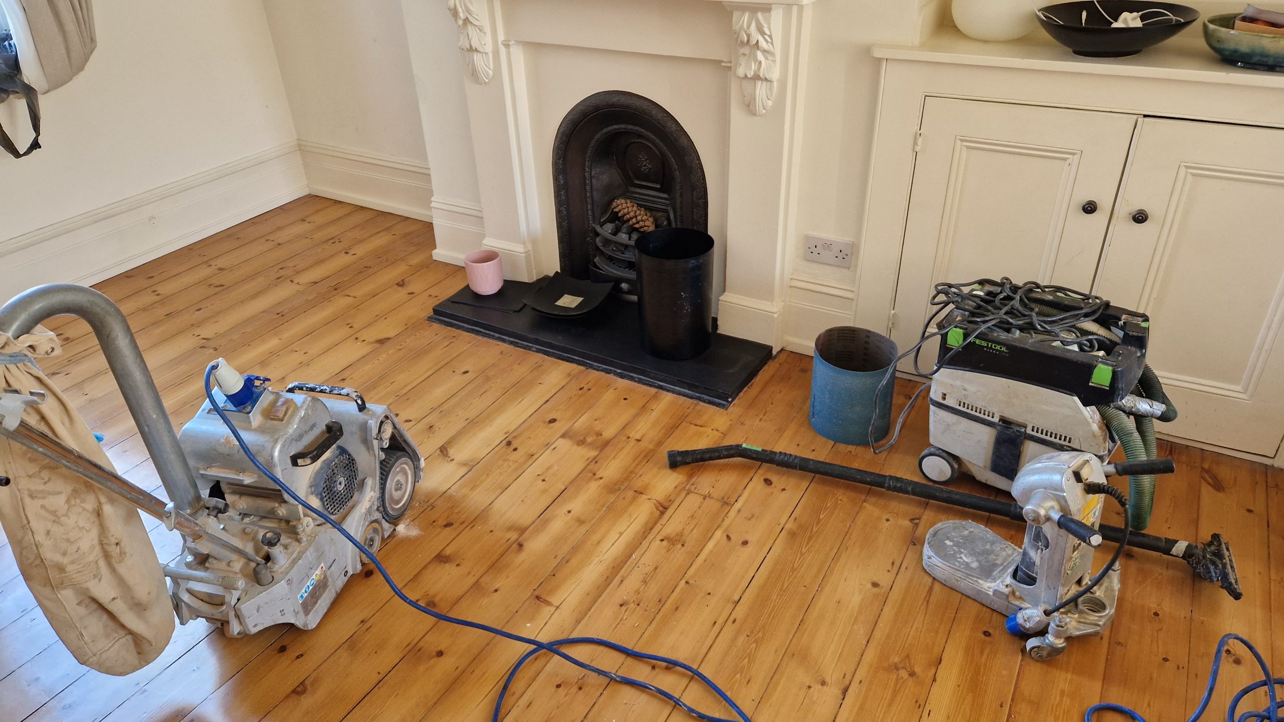Wood Floor Sanding machines positioned on Victorian pine floorboards in a Stamford Hill sitting room during restoration.