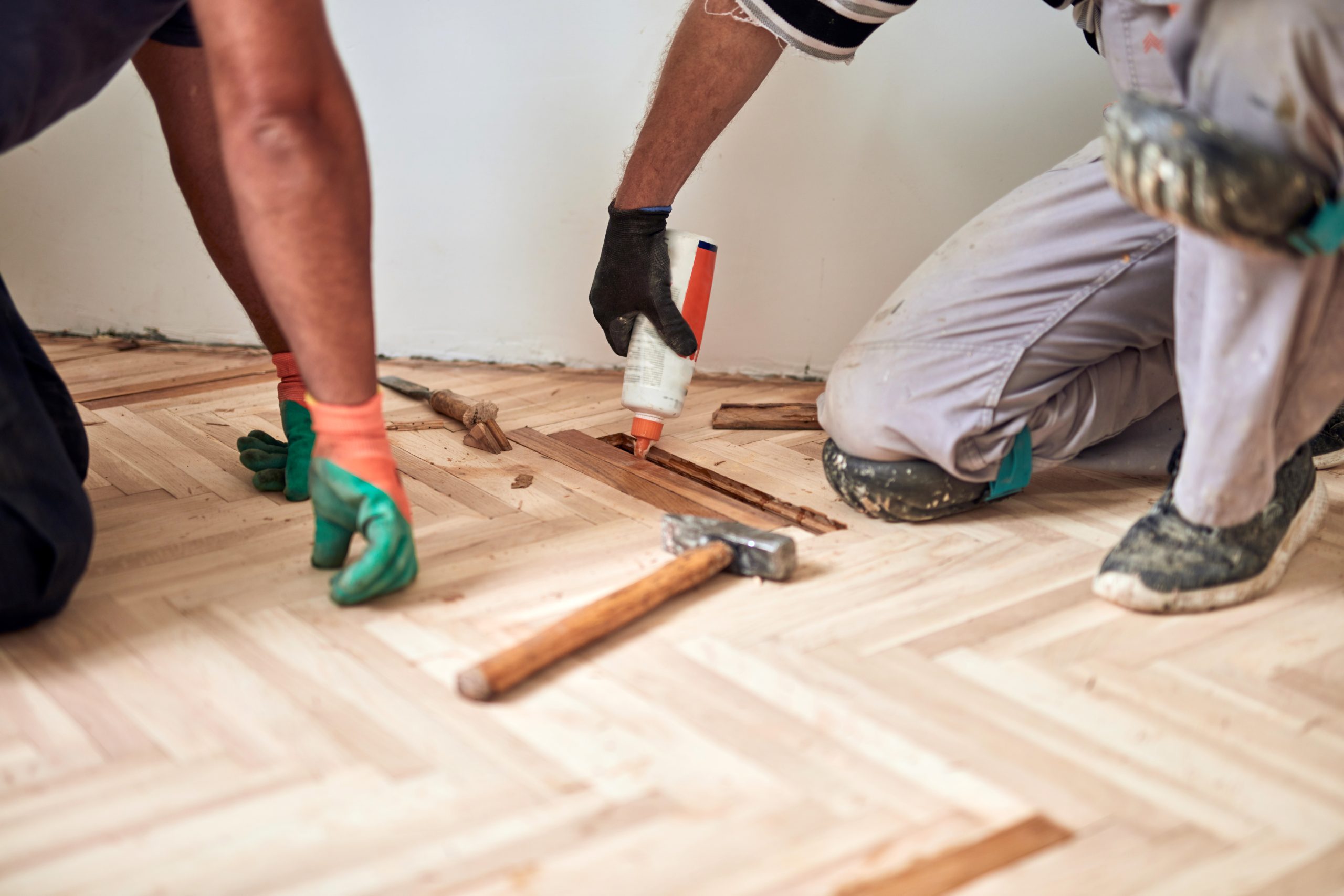 Hardwood Floor Refinishing in Stamford Hill – oak herringbone parquet blocks being repaired and glued before sanding and sealing.