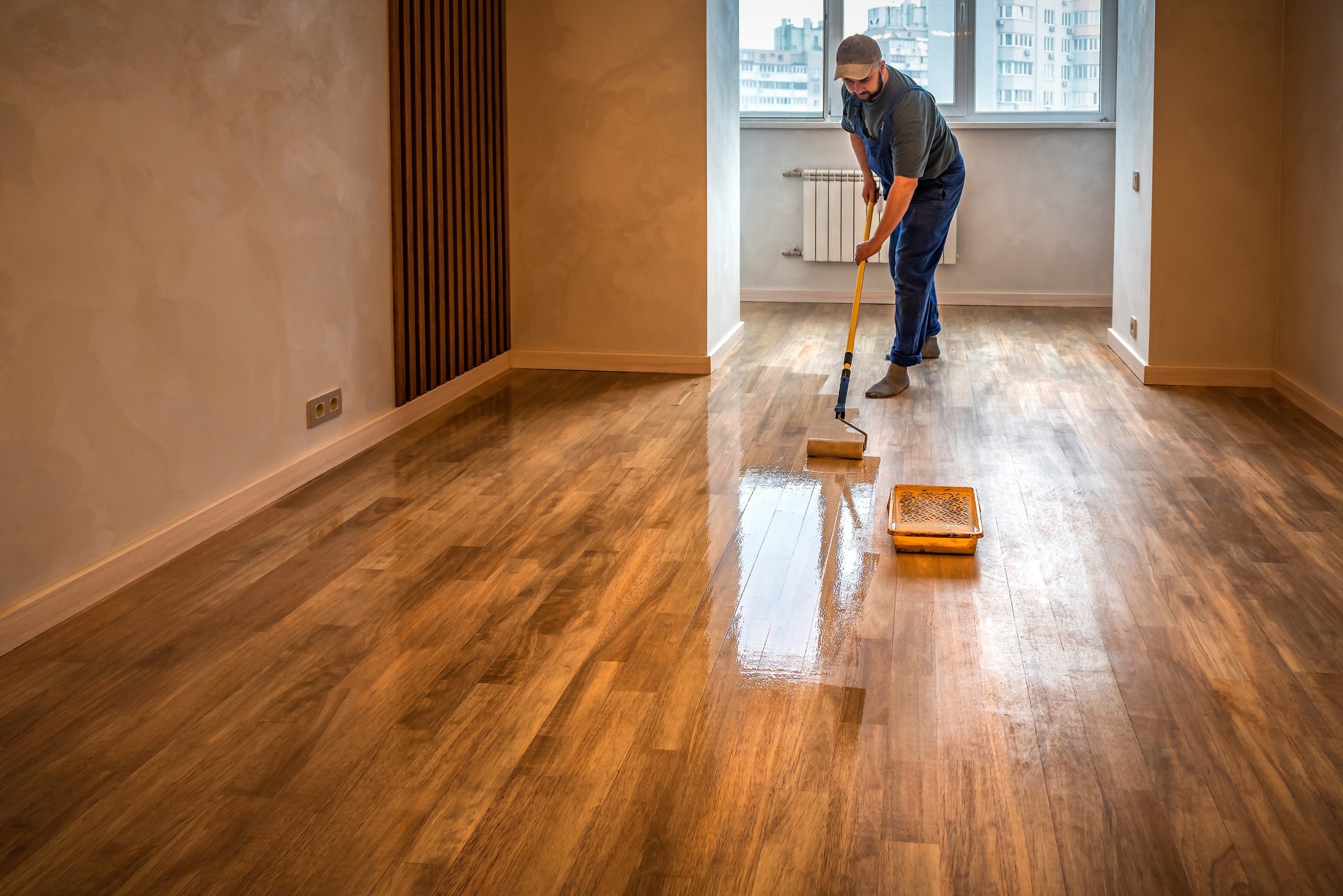 Hardwood Floor Refinishing in Stamford Hill on solid oak hardwood planks—technician applying a clear protective lacquer for a smooth, glossy finish.