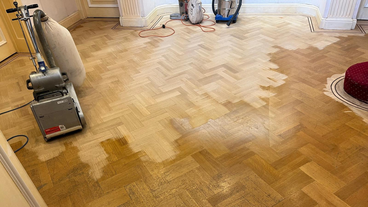 Parquet Floor Sanding in Stamford Hill on an oak herringbone parquet floor, showing sanding in progress with a professional drum sander smoothing worn blocks.